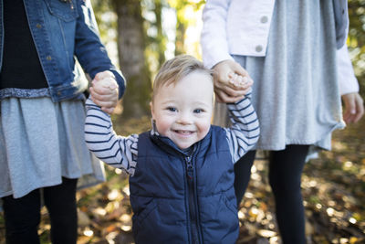 Midsection of girls holding sister hands while standing at park