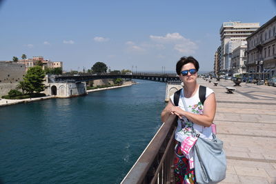 Smiling woman standing on pier against sky