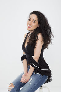 Portrait of smiling young woman sitting against white background