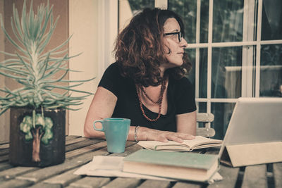 Woman sitting on table by window