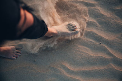 Low section of woman walking on sand dune