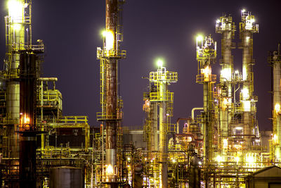 Low angle view of illuminated oil industry against sky at night