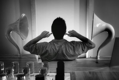 Rear view of man sitting on table at home