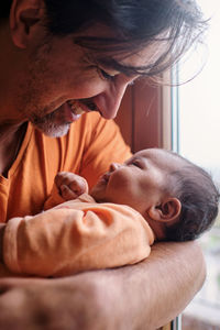 Bearded mature hispanic dad gently holding cute little baby at home