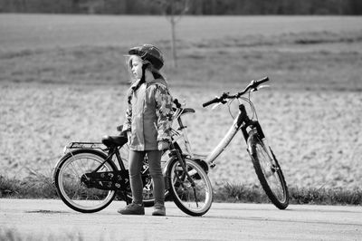 Little girl standing by bicycles on road
