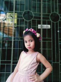 Portrait of flower girl standing against gate