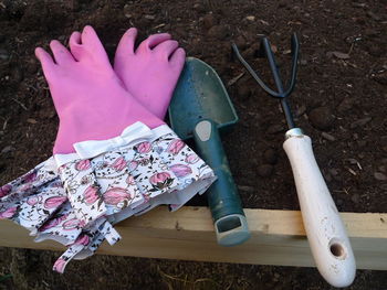 High angle view of gardening fork by gloves and shovel in garden