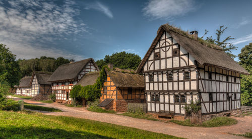 Houses by trees and buildings against sky