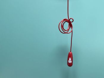 Close-up of rope hanging against blue wall