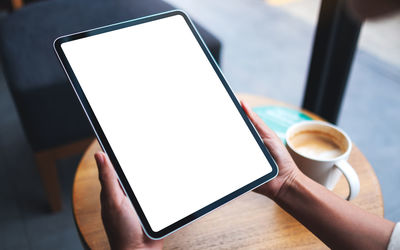 Mockup image of a woman holding digital tablet with blank white desktop screen