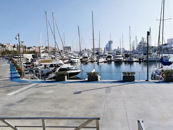 Sailboats moored at harbor against clear sky