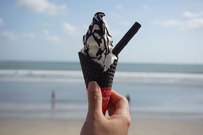 Close-up of hand holding ice cream cone at beach