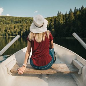 Rear view of woman sitting on boat against lake