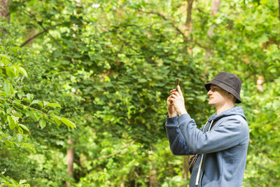 Tourist holding him smart phone and taking photo in the green summer forest. people and gadgets.