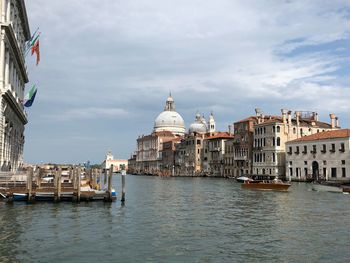 Canal amidst buildings amidst against cloudy sky