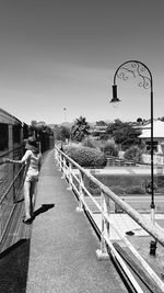 Rear view of woman walking on footpath against sky