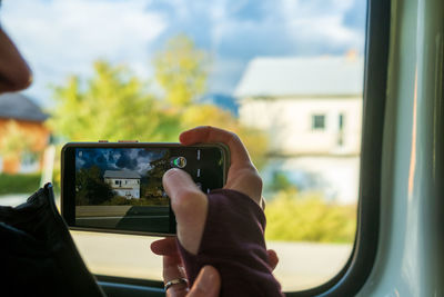 Cropped image of woman photographing through window