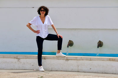 Full length of young woman standing against wall