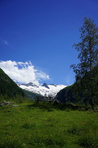 Scenic view of field by mountains against blue sky