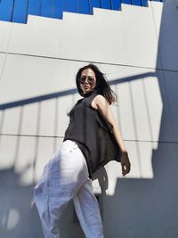 Portrait of smiling young woman standing against wall