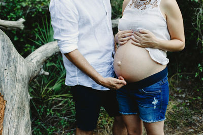 Midsection of woman touching tree