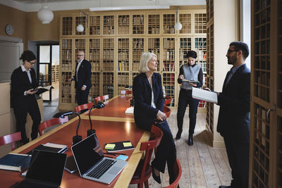 Male and female lawyers researching in board room at library