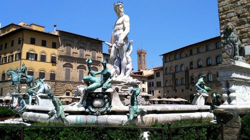 Statue against buildings in city against clear sky