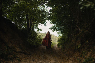 Rear view of woman walking amidst trees