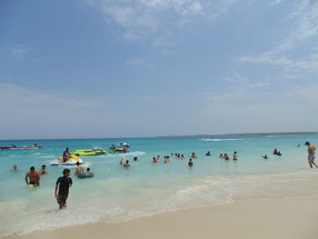 People enjoying at beach against sky