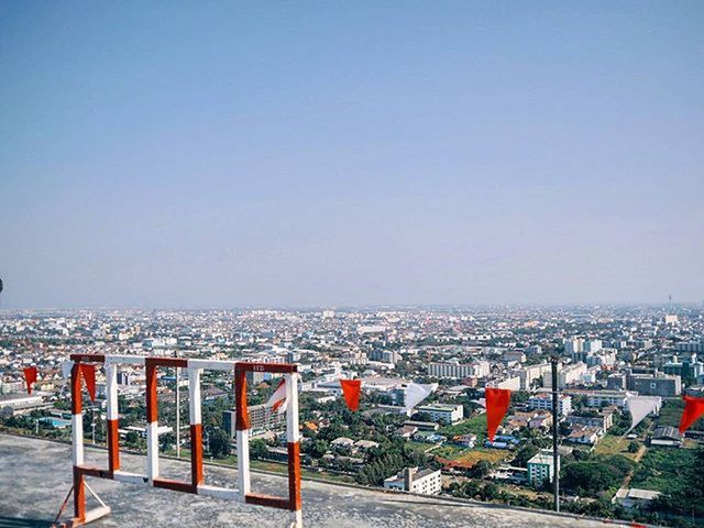 clear sky, copy space, built structure, building exterior, architecture, city, road, railing, street, cityscape, outdoors, blue, no people, empty, transportation, sky, day, residential structure, residential building, sea