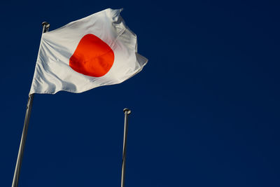 Low angle view of flag against clear blue sky