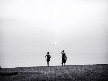 People walking on beach against clear sky