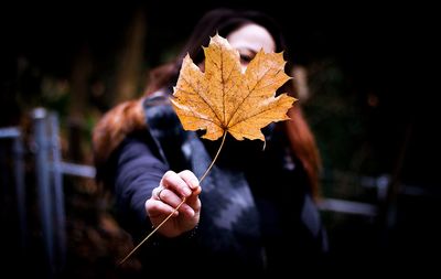 Close-up of hand holding autumn leaf