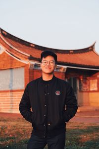 Portrait of young man standing against wall