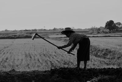 Man holding umbrella on field against sky