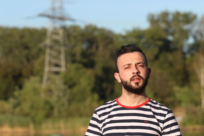 Portrait of young man standing against trees