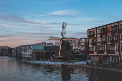 Buildings by river against sky