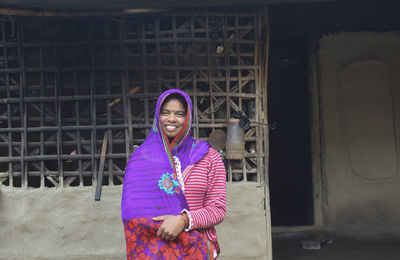 Portrait of smiling woman standing outside house