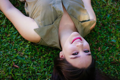 High angle portrait of young woman lying on grass