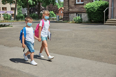 Girl and boy, brother and sister go to school for lessons  in protective masks. back to school