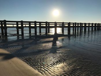 Pier over sea against clear sky during sunset