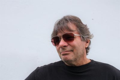 Portrait of young man wearing sunglasses against white background