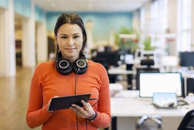 Portrait of confident businesswoman holding digital tablet in creative office