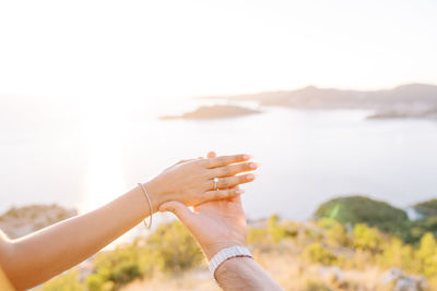 Cropped hand of woman gesturing against sky