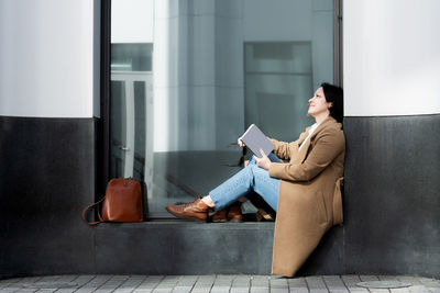 Woman using smart phone while sitting in laptop