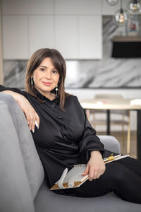 Portrait of young woman using mobile phone while sitting at home