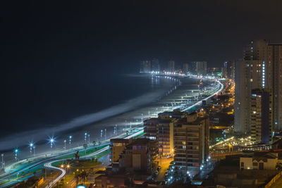 High angle view of buildings by sea at night