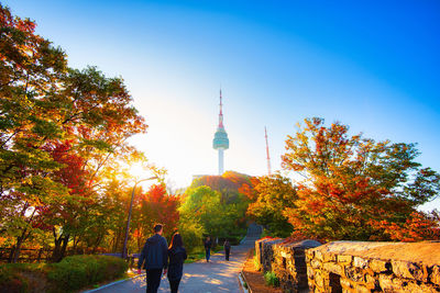Rear view of people walking on tower against sky during autumn