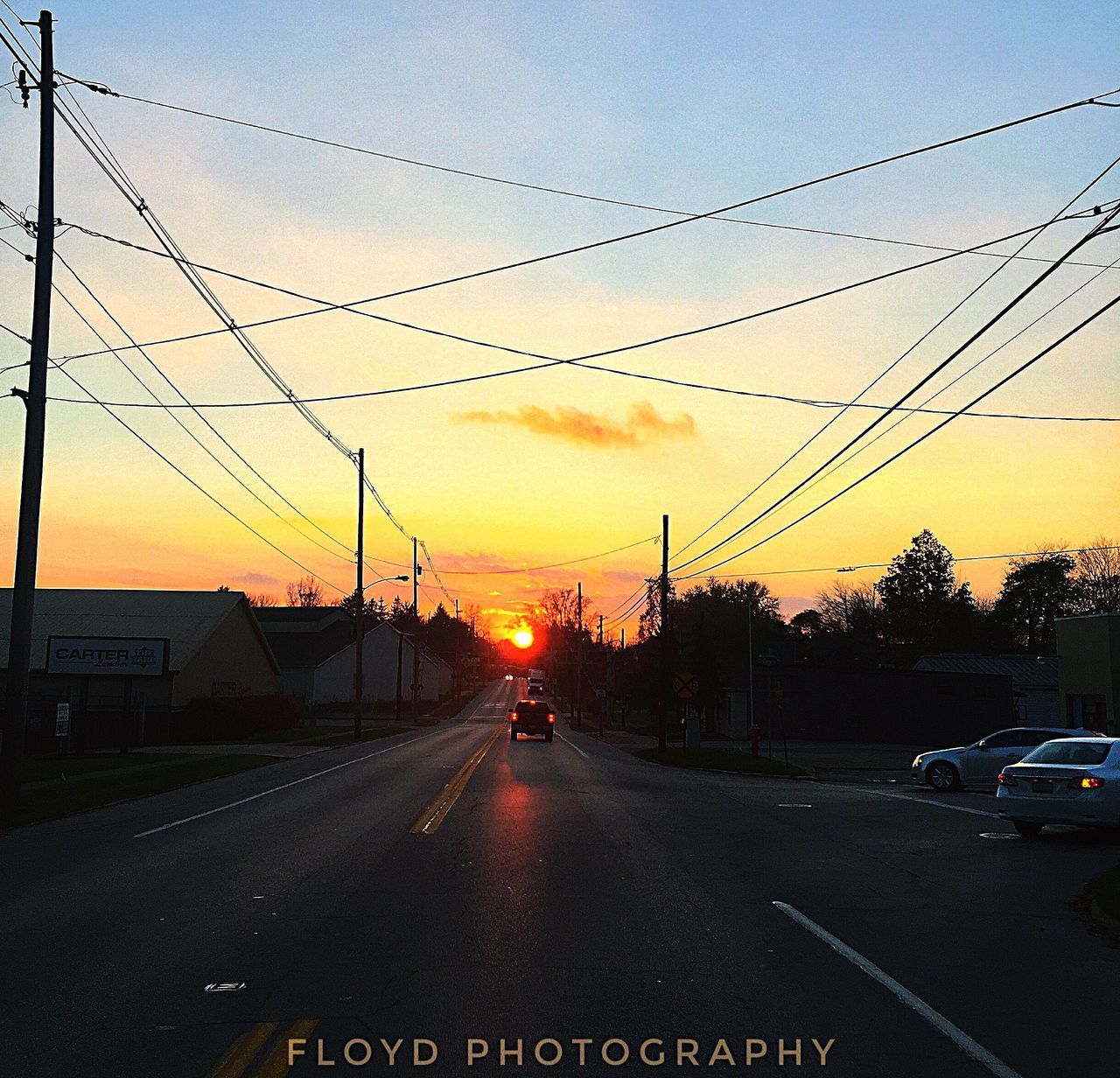 CARS ON WET STREET AGAINST SKY DURING SUNSET