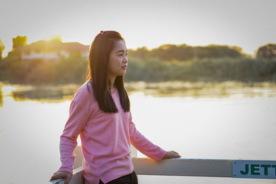 Portrait of young woman standing against lake